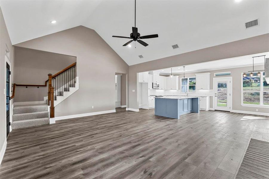 Unfurnished living room featuring ceiling fan, high vaulted ceiling, and hardwood / wood-style floors