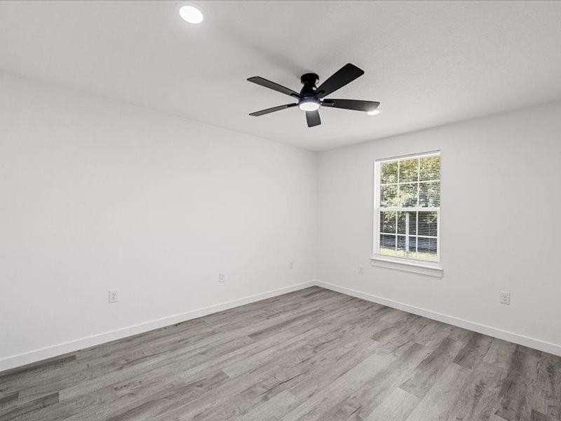 Empty room featuring light wood finished floors, ceiling fan, and recessed lighting