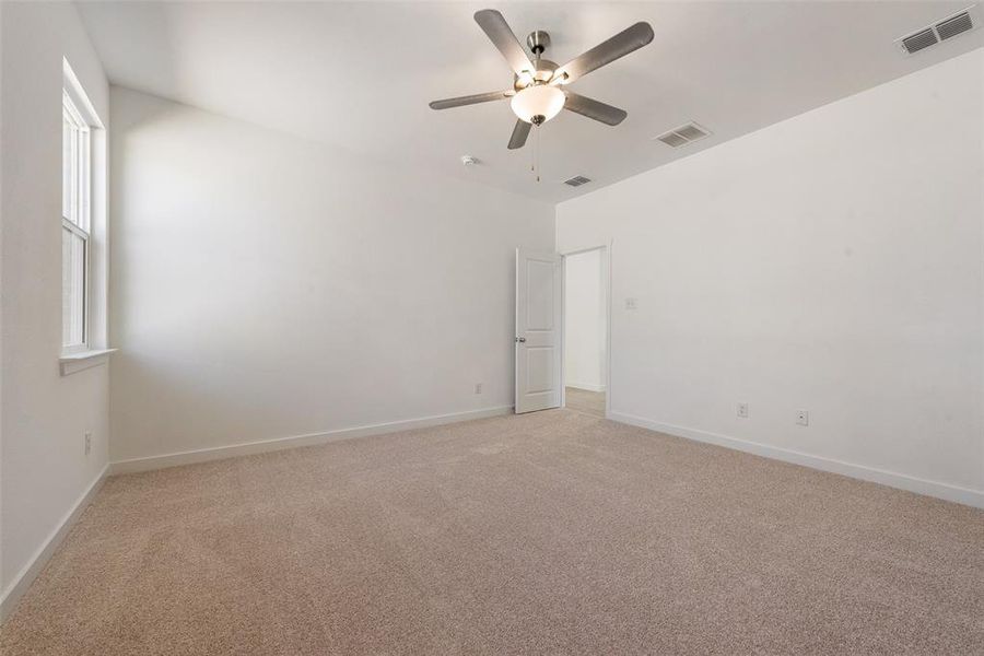 Empty room with ceiling fan and light carpet