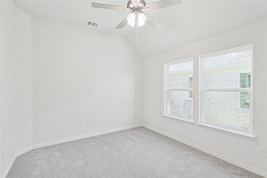 Carpeted spare room featuring ceiling fan and vaulted ceiling