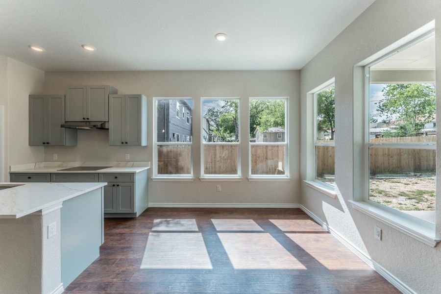 Spacious open-concept area featuring wood-finish flooring, recessed lighting, and large windows