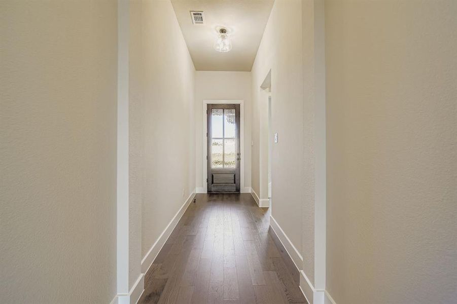 Hallway with dark wood-type flooring and baseboards Hallway with dark wood-type flooring and baseboards