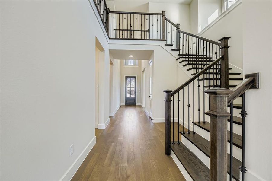 Entrance foyer with wood finished floors, a high ceiling, and stairway