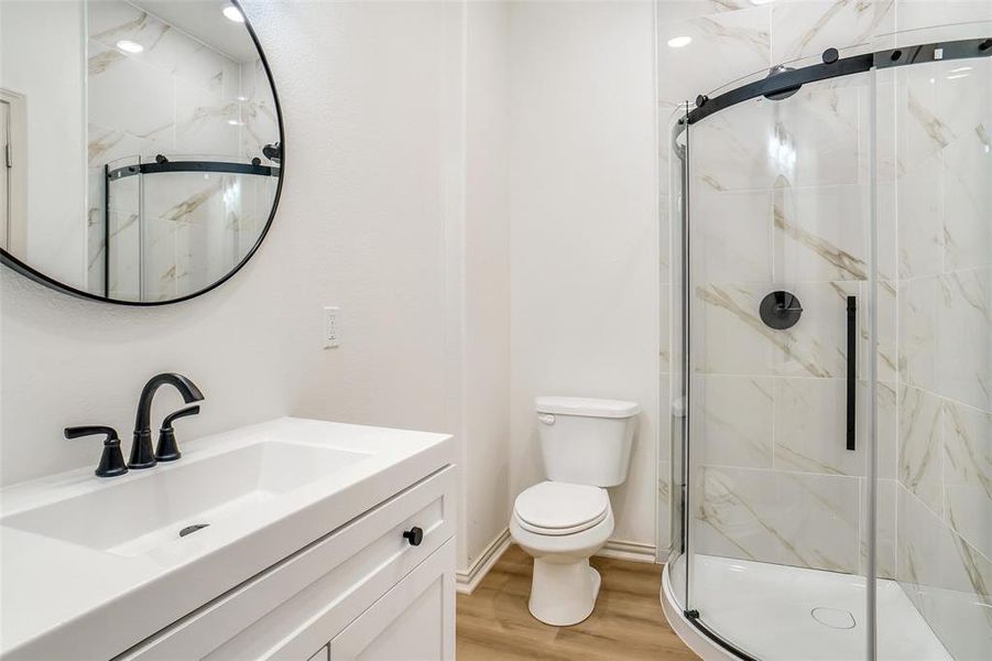 Bathroom featuring vanity, toilet, wood-type flooring, and a shower with shower door