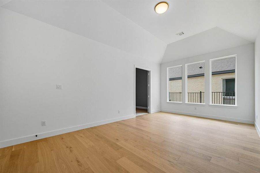Spare room with light wood-style floors and vaulted ceiling Spare room with light wood-style floors and vaulted ceiling