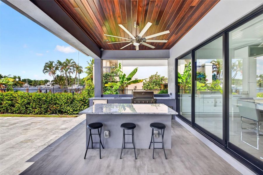 Covered patio w/ T&G ceilings, fans, fire pit seating and outdoor kitchen overlooks the gorgeous wide New River views and pool area