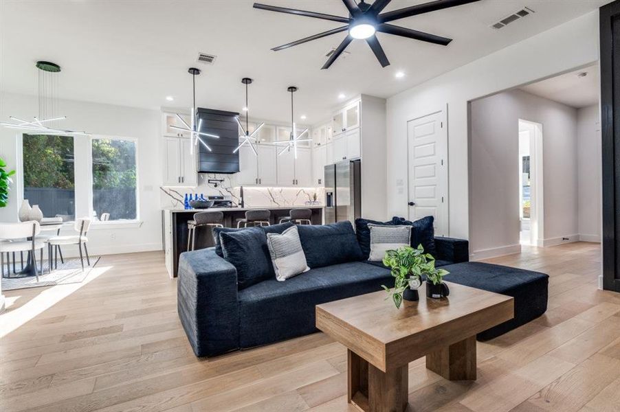 Living area with light wood finished floors, a ceiling fan, a chandelier, and recessed lighting Living area with light wood finished floors, a ceiling fan, a chandelier, and recessed lighting