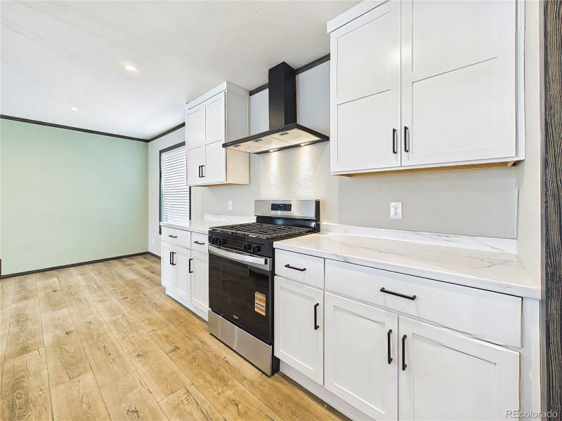 Kitchen – Range & Hood Detail – Modern cooking area featuring a stainless steel gas range, sleek vent hood, and surrounding shaker cabinetry.