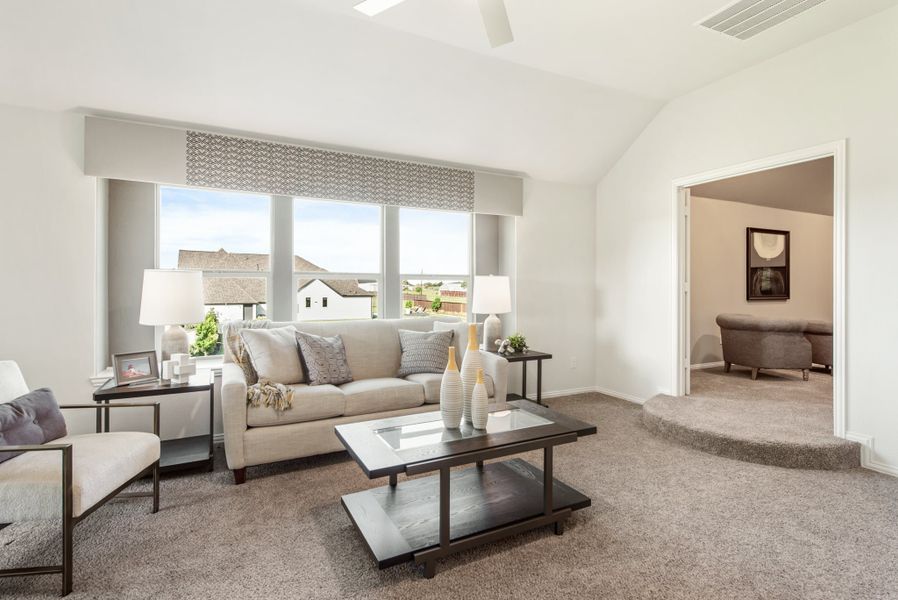 Living room with vaulted ceiling, large windows, beige sofa, and dark wood coffee table on carpet