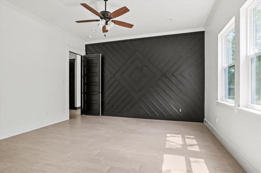 Unfurnished room featuring crown molding, light wood-type flooring, an accent wall, and ceiling fan