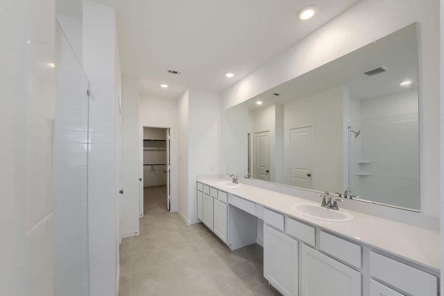 Luxurious oversized shower, convenient linen closet, and cozy seating area.