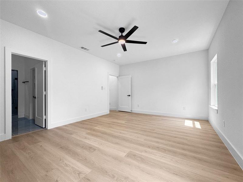 Unfurnished bedroom featuring light wood-type flooring, a ceiling fan, recessed lighting, and ensuite bath