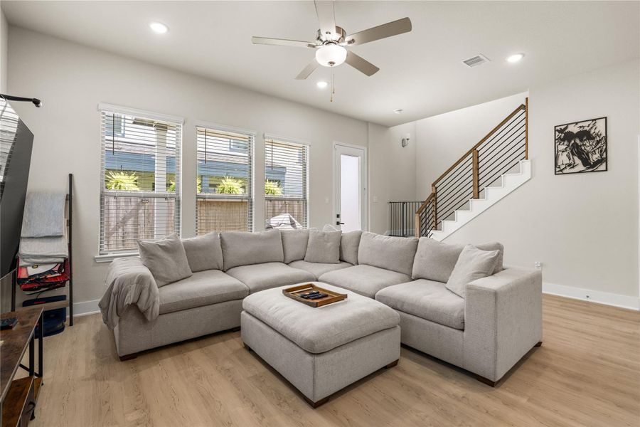 Warm wood accents and modern iron balusters bring architectural character to the staircase, complementing the durable luxury vinyl plank flooring that extends throughout the main living areas.