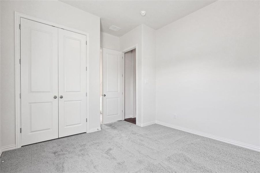 Unfurnished bedroom featuring a closet and light colored carpet