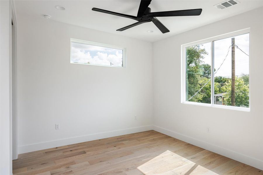 This bedroom boasts crisp new paint, a ceiling fan, and recessed lighting, creating a fresh, inviting space that blends comfort with modern style.