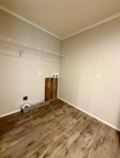 Dedicated utility space featuring wood-finish flooring, light neutral walls, white trim, and a wire shelving system