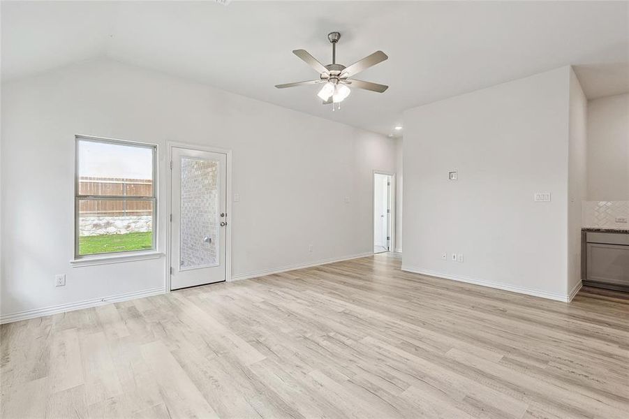 Unfurnished living room featuring light hardwood / wood-style floors, ceiling fan, and vaulted ceiling