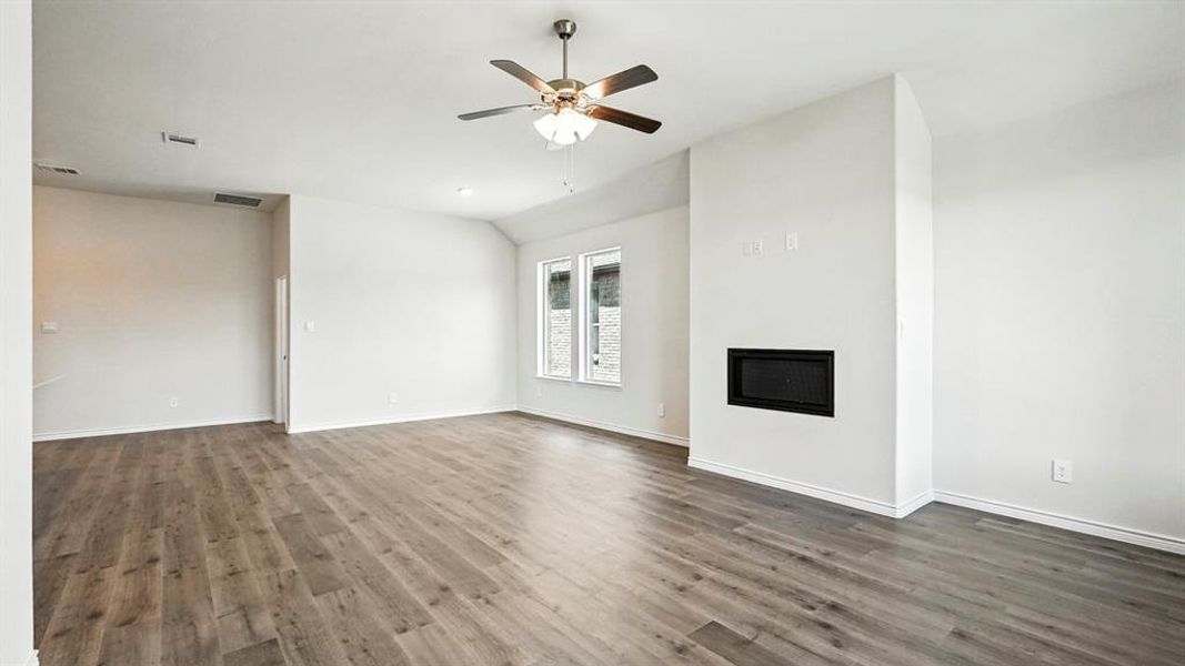 Unfurnished living room featuring a glass covered fireplace, wood finished floors, ceiling fan, and lofted ceiling