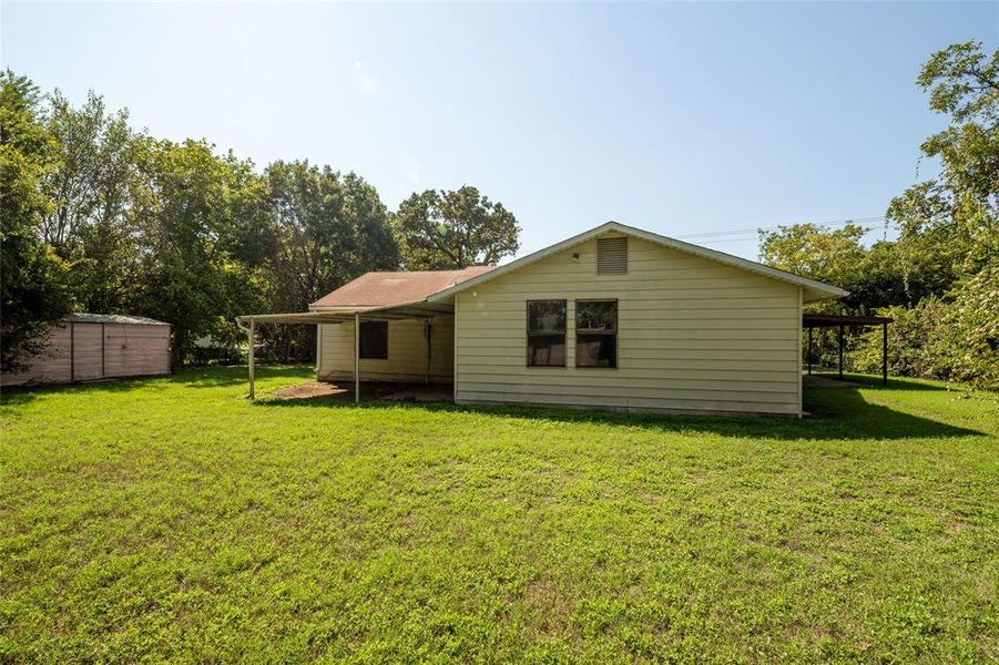 Back of house featuring a lawn and a storage unit