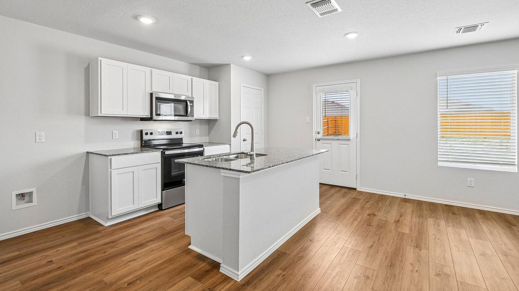 A well-appointed kitchen features stainless steel appliances, granite countertops, and a central island with a sink.