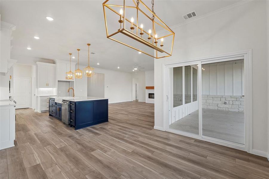 Kitchen featuring blue cabinetry, white cabinets, pendant lighting, a chandelier, and open floor plan