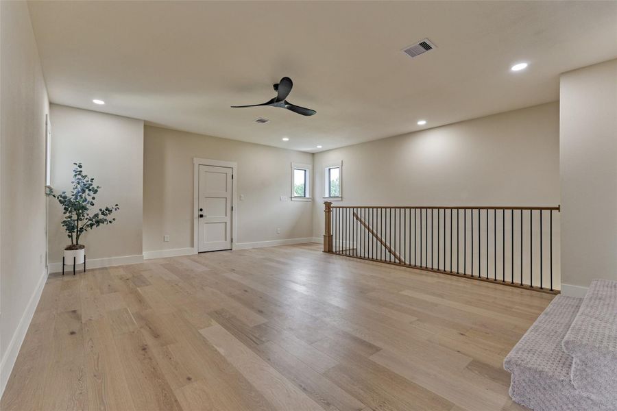 Expansive upstairs game room in rich white oak engineered hardwood — plenty of room for a pool table, with steps leading up to the next space. Flexible enough for whatever your family needs: play, lounge, or multipurpose. Expansive upstairs game room in rich white oak engineered hardwood — plenty of room for a pool table, with steps leading up to the next space. Flexible enough for whatever your family needs: play, lounge, or multipurpose.
