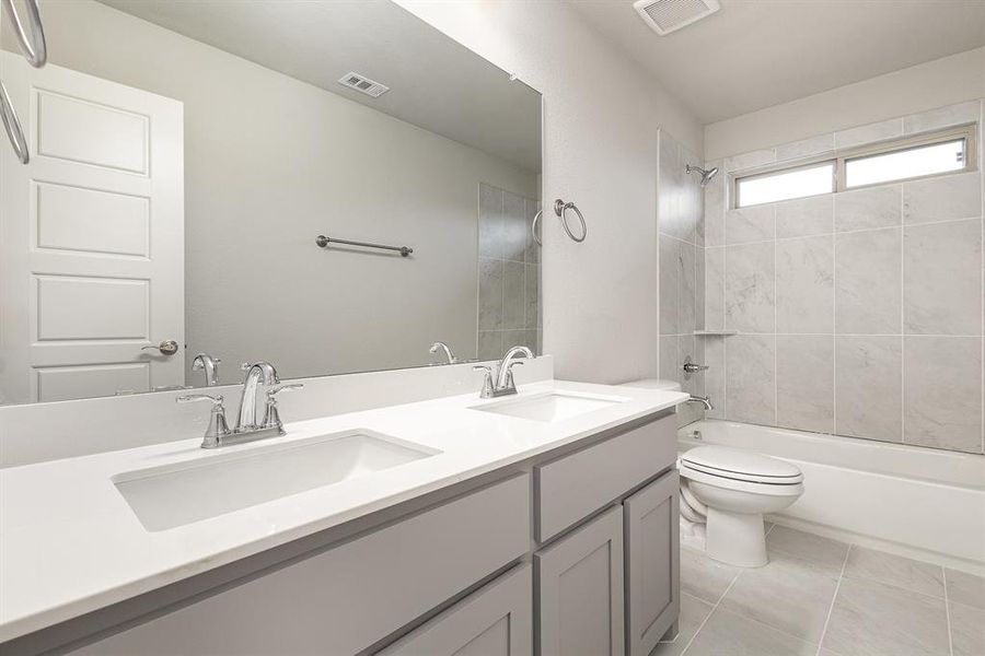 Full bathroom featuring tile patterned floors, toilet, vanity, and tiled shower / bath