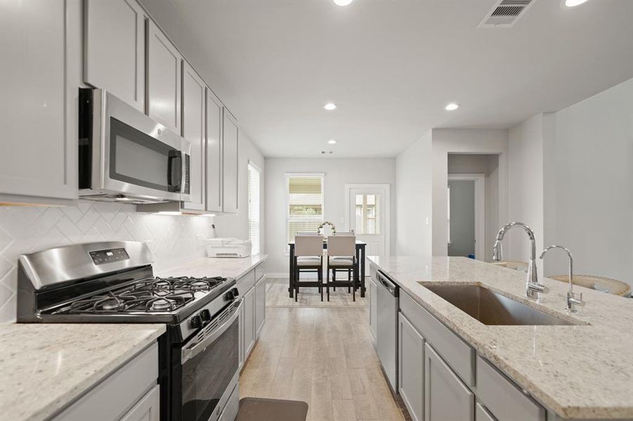 Your chef inspired kitchen awaits! Features include quartz countertops paired with a coordinating tiled backsplash, stainless steel appliances, rich cabinets, under cabinet lighting, recessed lighting, and a sprawling island with breakfast bar seating.