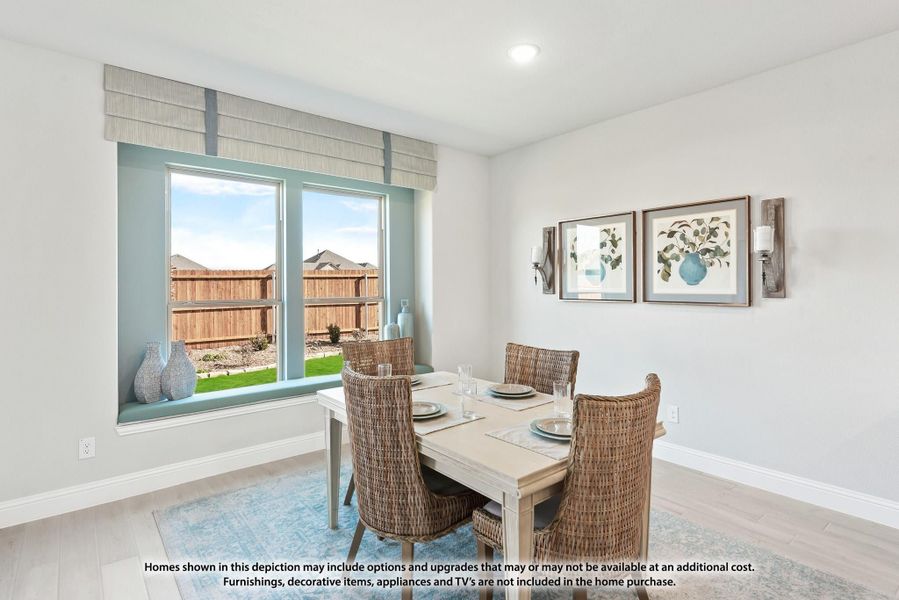Dining room with light wood table, wicker chairs, large window, and hardwood floors