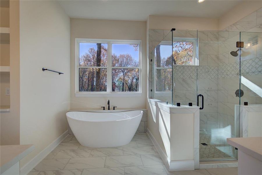 Primary bath is a spa retreat, with large soaking tub, generous glass-walled step-in shower, tile flooring.