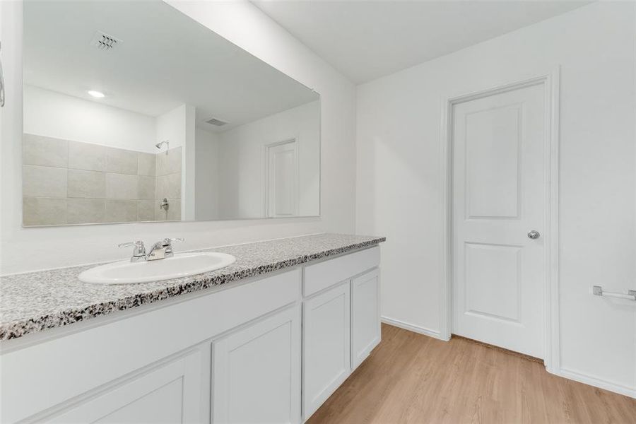 Bathroom featuring a tile shower, wood-type flooring, and vanity