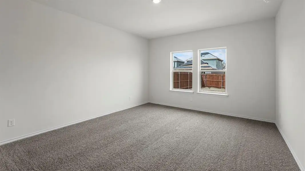 This room features light gray carpet flooring, white walls, and two windows providing natural light