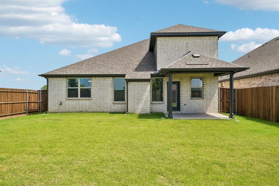 Expansive backyard featuring a manicured lawn, brick exterior, covered patio, and a privacy fence Expansive backyard featuring a manicured lawn, brick exterior, covered patio, and a privacy fence