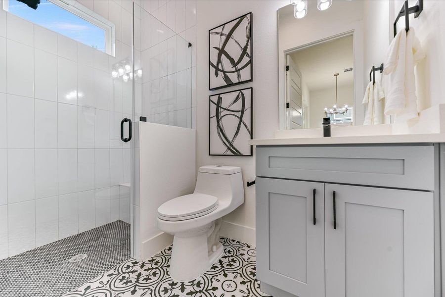 Bold patterns meet modern minimalism. This bathroom pops with geometric floor tiling and a slate-blue vanity.