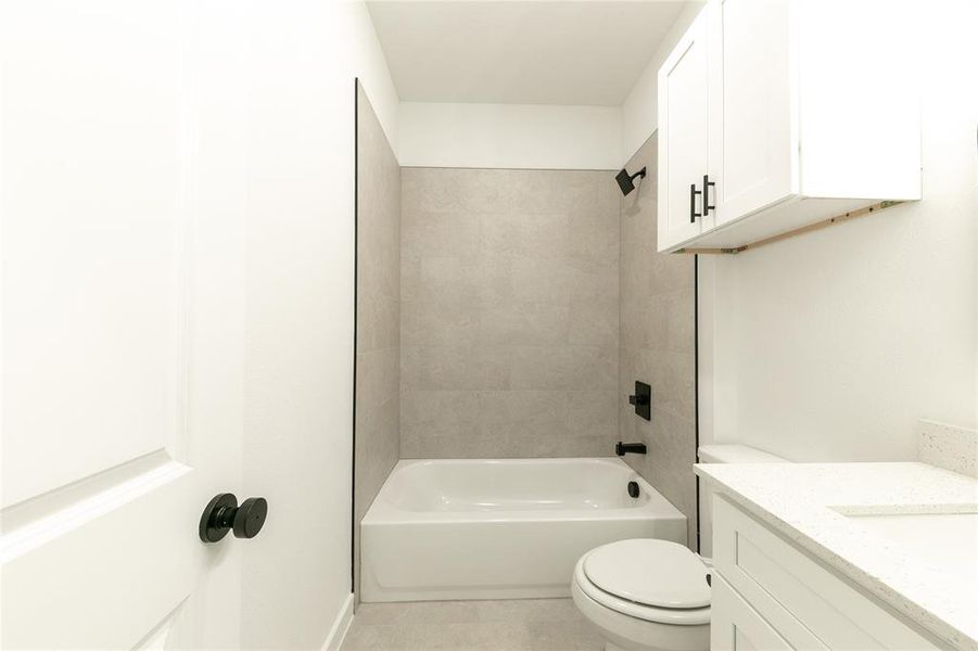 Full bathroom featuring toilet, vanity, tile patterned flooring, and shower / tub combination