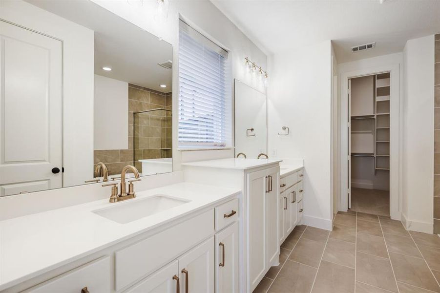 Dual vanity with white cabinetry, integrated sinks, and brushed bronze fixtures