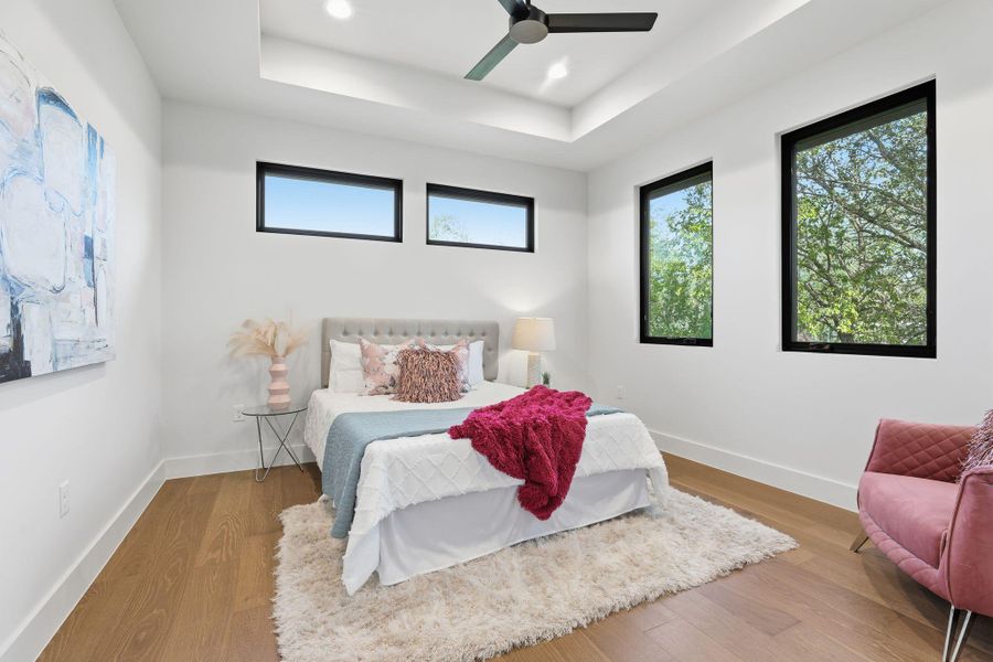 Bedroom with wood finished floors, ceiling fan, a raised ceiling, and recessed lighting Bedroom with wood finished floors, ceiling fan, a raised ceiling, and recessed lighting