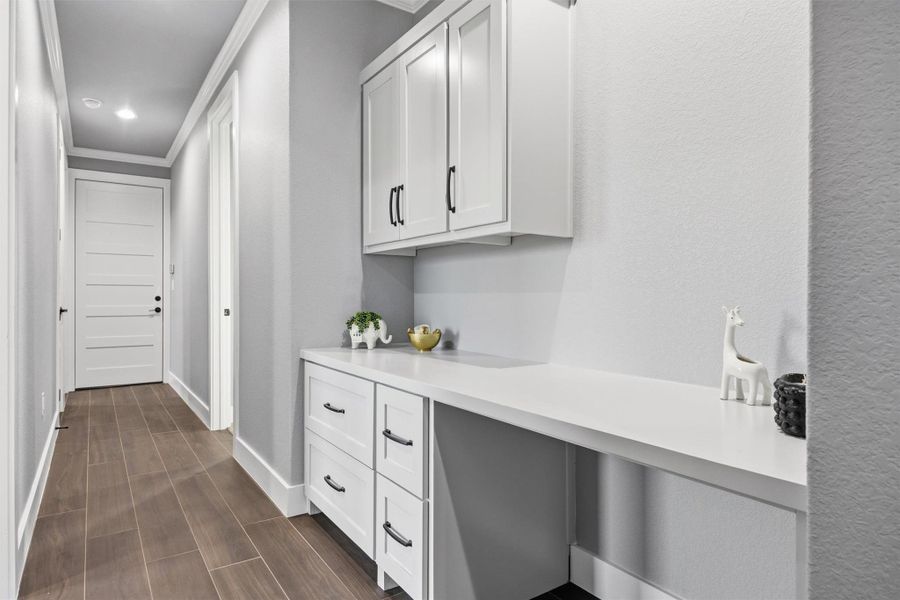 Hallway featuring wood finish floors, crown molding, and recessed lighting, built ins and desk for office or kids desk.