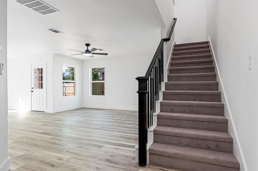 Stairs featuring wood finished floors and a ceiling fan