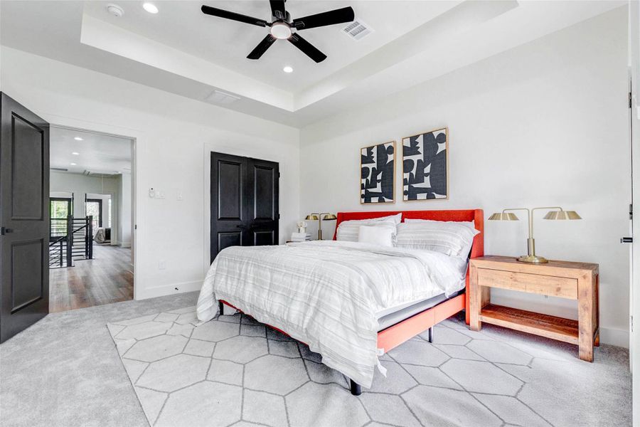 Clean lines and a neutral palette define the bedroom, which includes a modern ceiling fan and large walk-in closet.