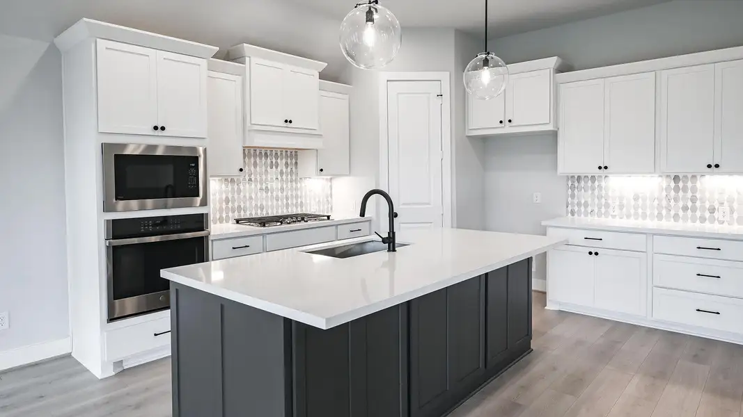 Kitchen with white cabinets, a center island with sink, tasteful backsplash, stainless steel appliances, and decorative light fixtures