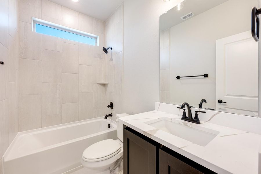 Bathroom with tiled tub-shower combo, white quartz vanity, dark cabinets, and matte black fixtures Bathroom with tiled tub-shower combo, white quartz vanity, dark cabinets, and matte black fixtures