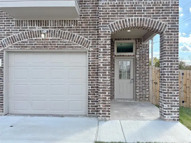 Doorway to property with brick siding and a garage