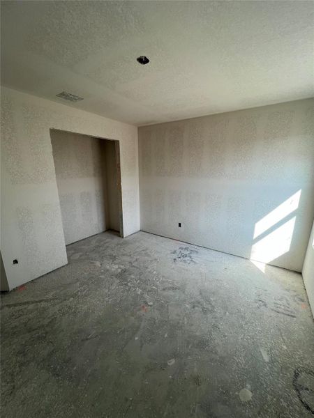 Unfurnished bedroom featuring a textured ceiling and unfinished concrete flooring