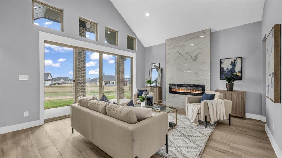 Living room with plenty of natural light, a high end fireplace, high vaulted ceiling, light wood finished floors, and recessed lighting