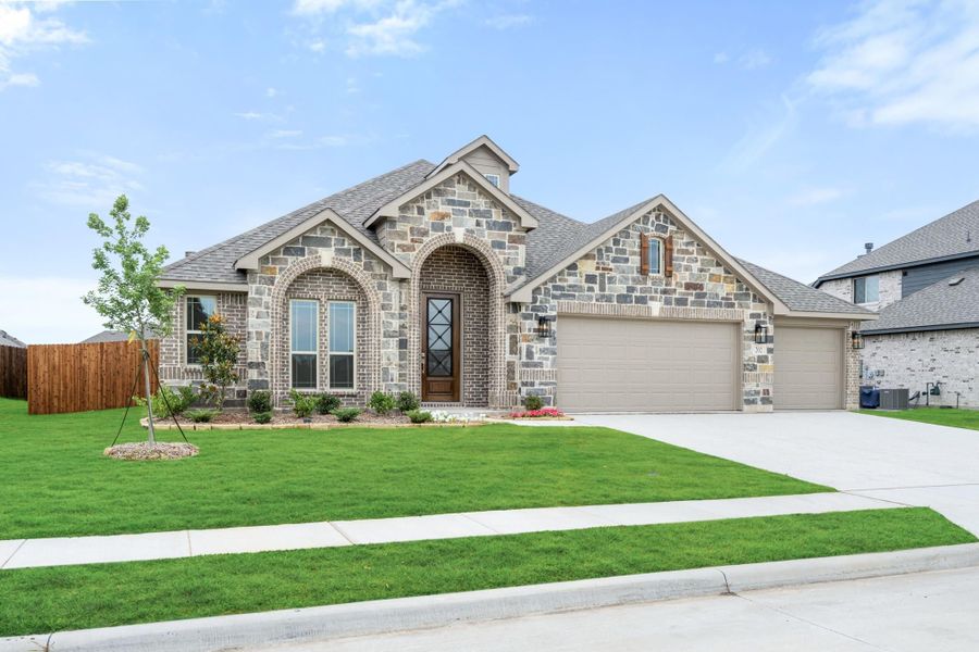 Single-story home with stone and brick exterior, arched entryway, two-car garage, and green front lawn