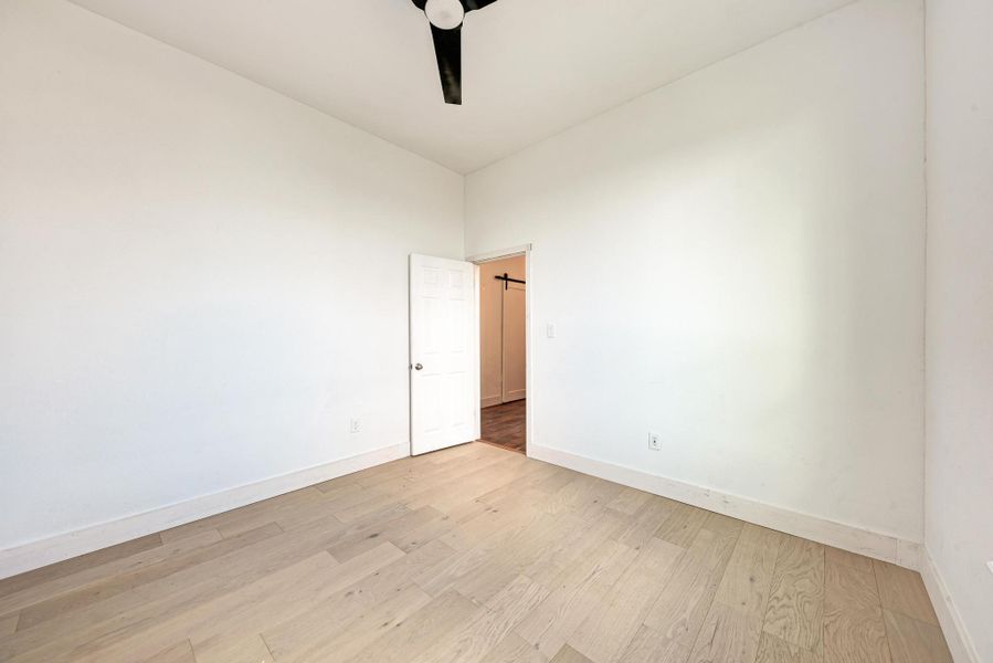 Smooth wood floors and crisp white walls define this clean, minimalist bedroom space.