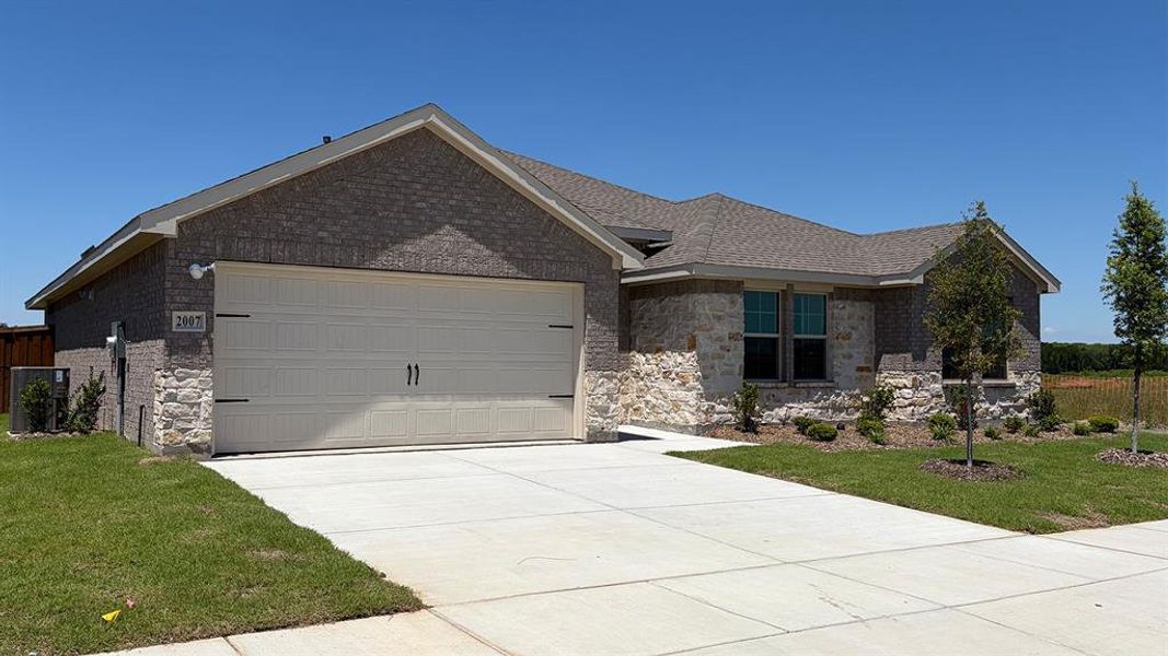 Modern single-story residence showcasing a two-car garage, brick and stone facade, concrete driveway, and established front landscaping