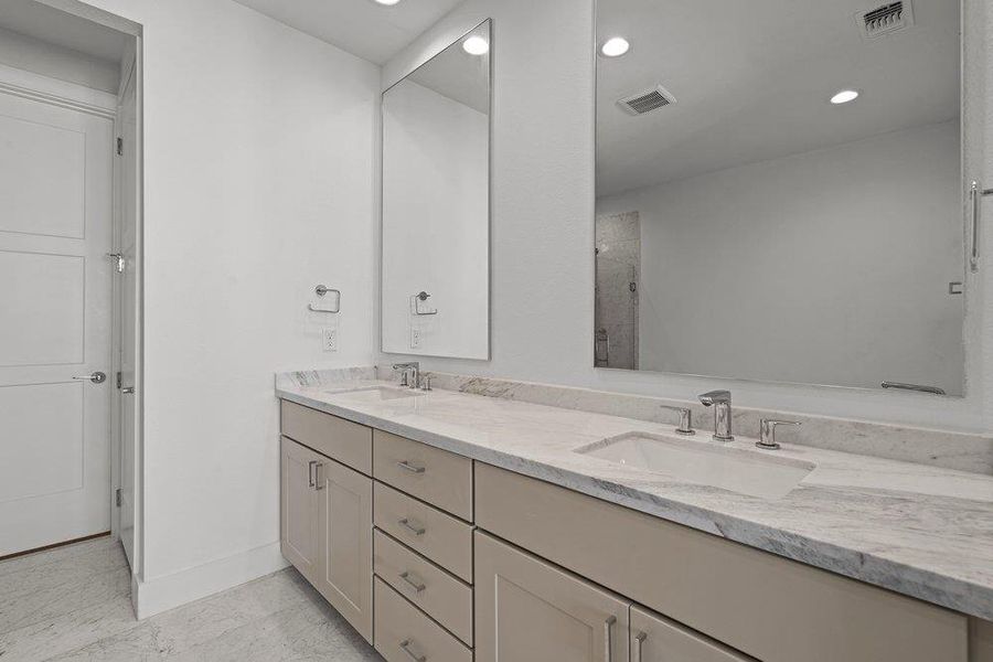 Double undermount sinks accent a stone vanity top with dual mirrors above. Double undermount sinks accent a stone vanity top with dual mirrors above.