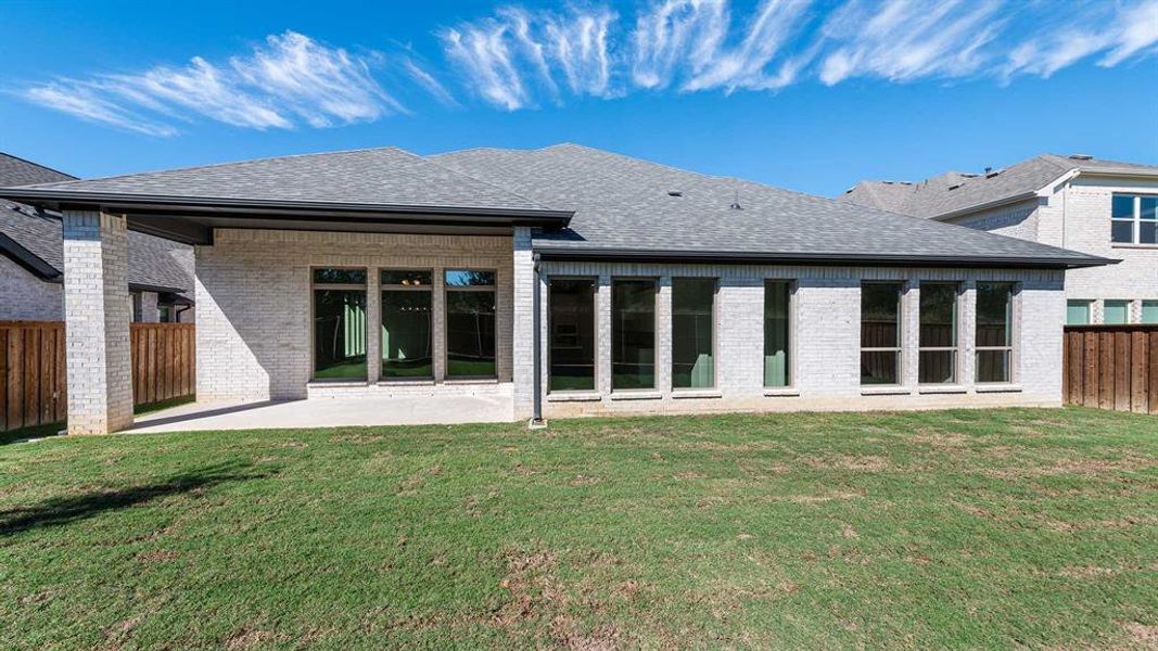 Rear view of house featuring a patio and a lawn